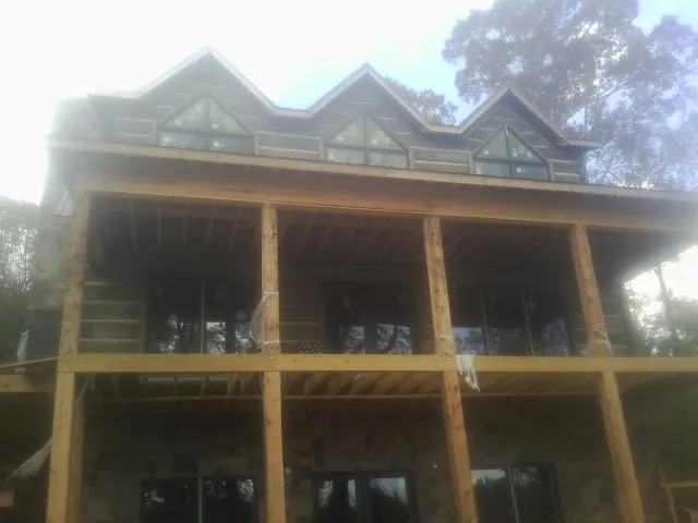 Dormers and porch framing on a large log home under construction — Roof Coating work by our crew in Edgerton