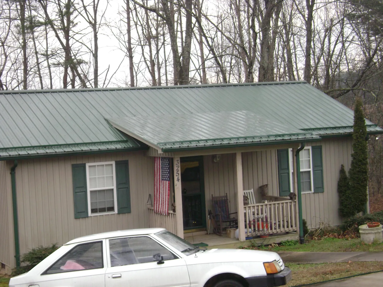 Green metal roof and front porch on a tan sided cottage in Edgerton